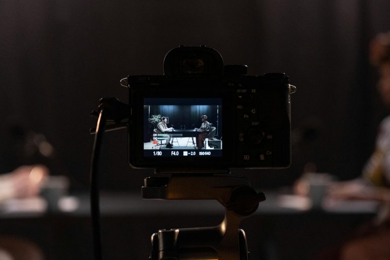 Close-up of a camera recording a podcast interview in a studio setting.