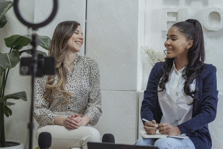 Two women engaged in a lively conversation in a professional interview setting.